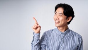 白背景でストライプシャツを着た若い男性が上を指さす