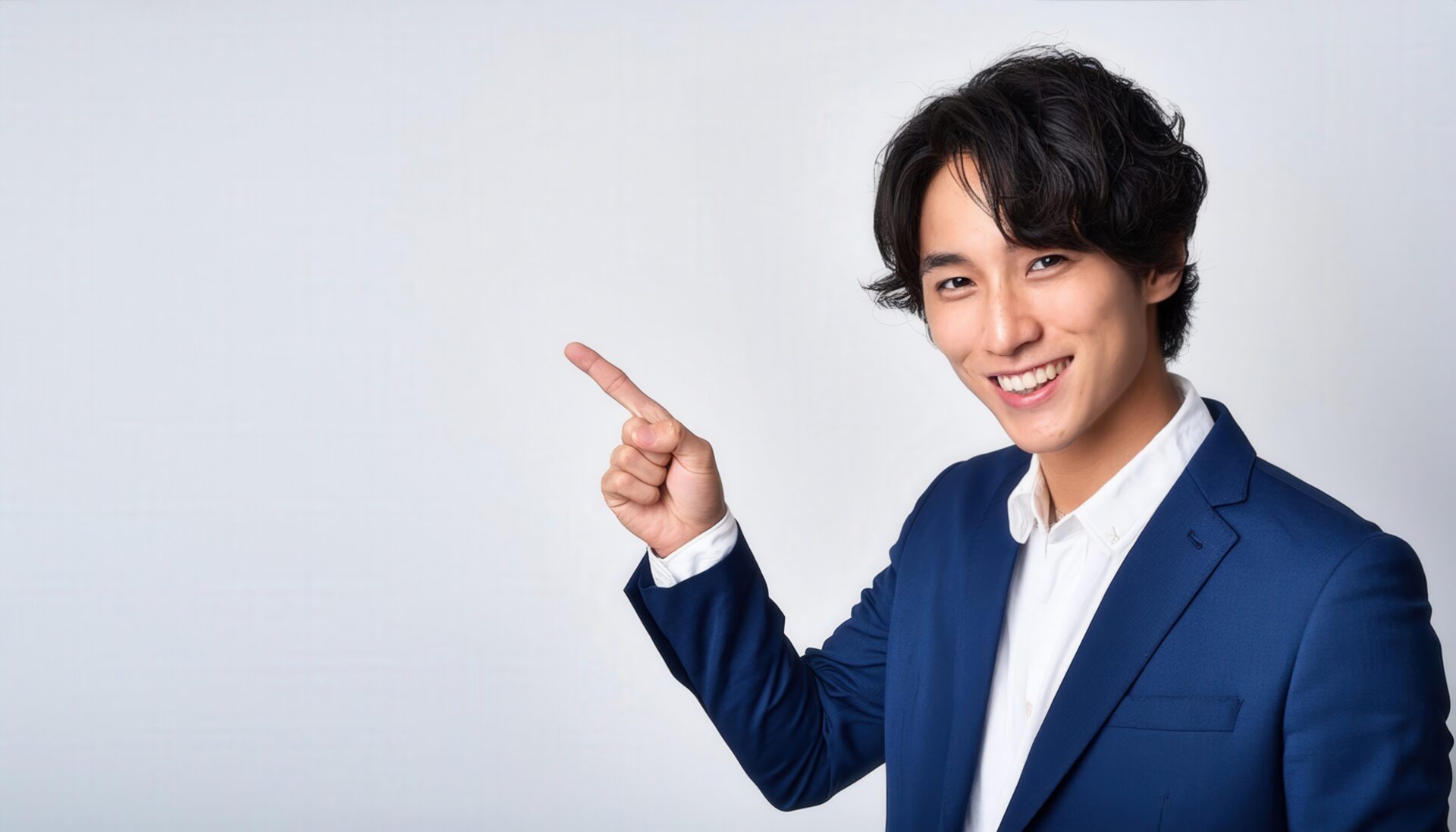 白背景でネイビースーツを着た若い男性が指をさす