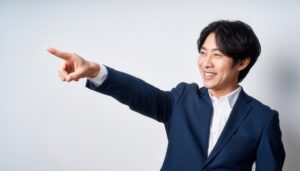 白背景でネイビースーツを着た若い男性が右を指さす