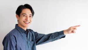 白背景でストライプシャツを着た若い男性が横を指さす