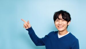 青背景で青いセーターを着た若い男性が右を指さす