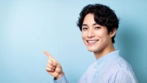 青背景でストライプシャツを着た若い男性が右を指さす