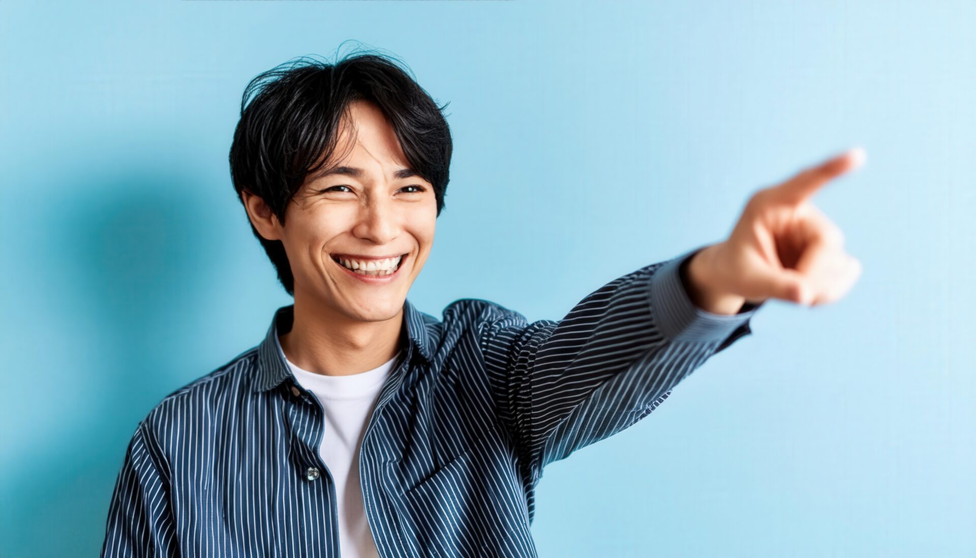 青背景でストライプシャツを着た若い人が横を指さす