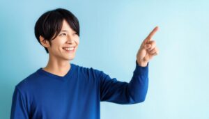 青背景で青いセーターを着た若い人が右を指さす