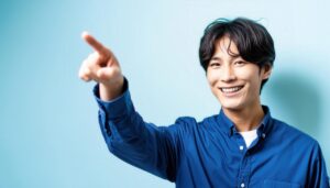 青背景でブルーのシャツを着た若い人が前方を指さす
