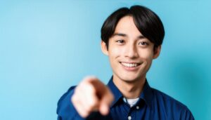 青背景でネイビーのシャツを着た若い人が手前を指さす