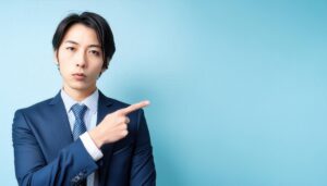 青背景でネイビースーツを着た若い人が左を指さす