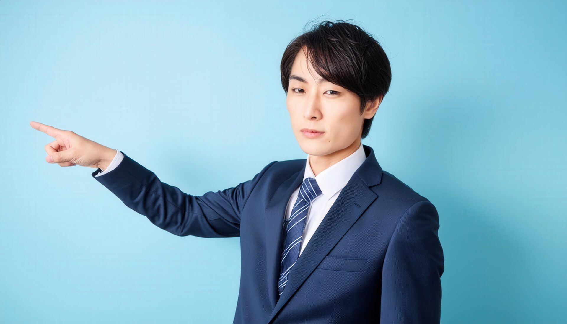 水色背景でネイビーのスーツを着た若い男性が前方を指さす
