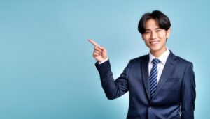 水色背景でネイビーのスーツを着た若い男性が前方を指さす