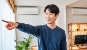 室内でネイビーのセーターを着た若い男性が横を指さす