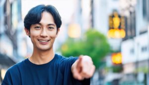 街中で黒いTシャツを着た若い男性がこちらを指さす