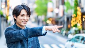 スーツ姿で指をさす笑顔の若い男性