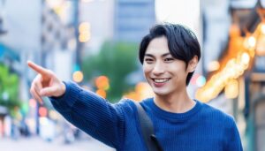 セーター姿で指をさす笑顔の若い男性