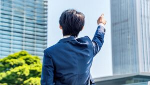 大きなビルを指さす後ろ姿の若い男性