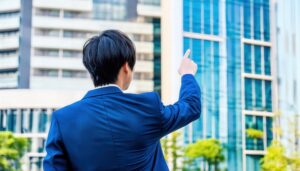 高層オフィス街で指をさす後ろ姿の若い男性