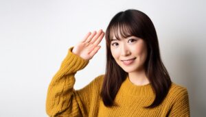 マスタード色のセーターで敬礼ポーズをする若い女性