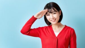 赤いニットで敬礼ポーズをする若い女性(青背景)