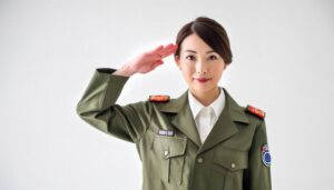 白背景で緑の軍服姿で敬礼する人物