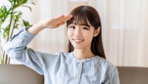 室内でストライプのトップスを着て敬礼する人物