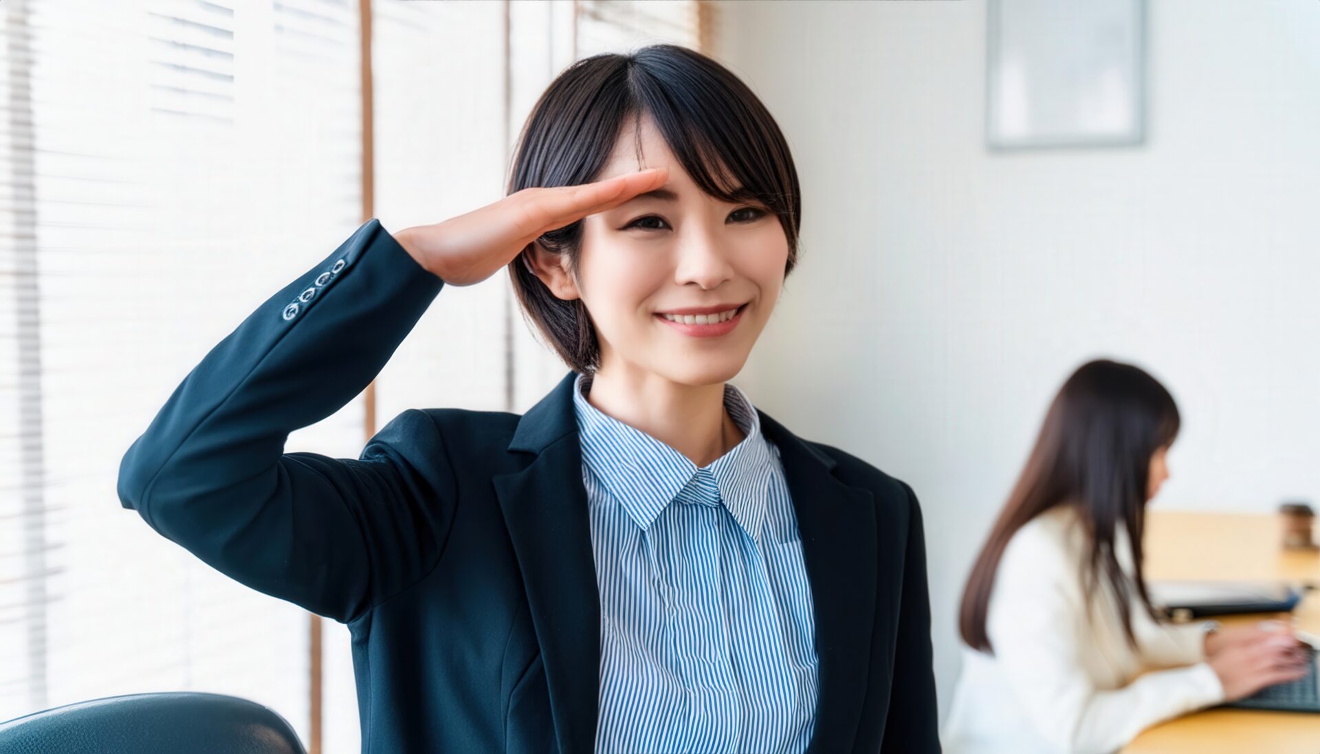 オフィスでネイビーのジャケットを着て敬礼する人物