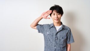 白背景でチェックシャツを着て敬礼する人物