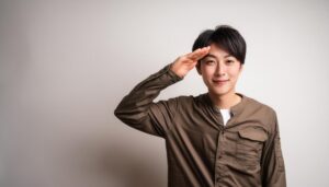 白背景でブラウンのシャツを着て敬礼する人物