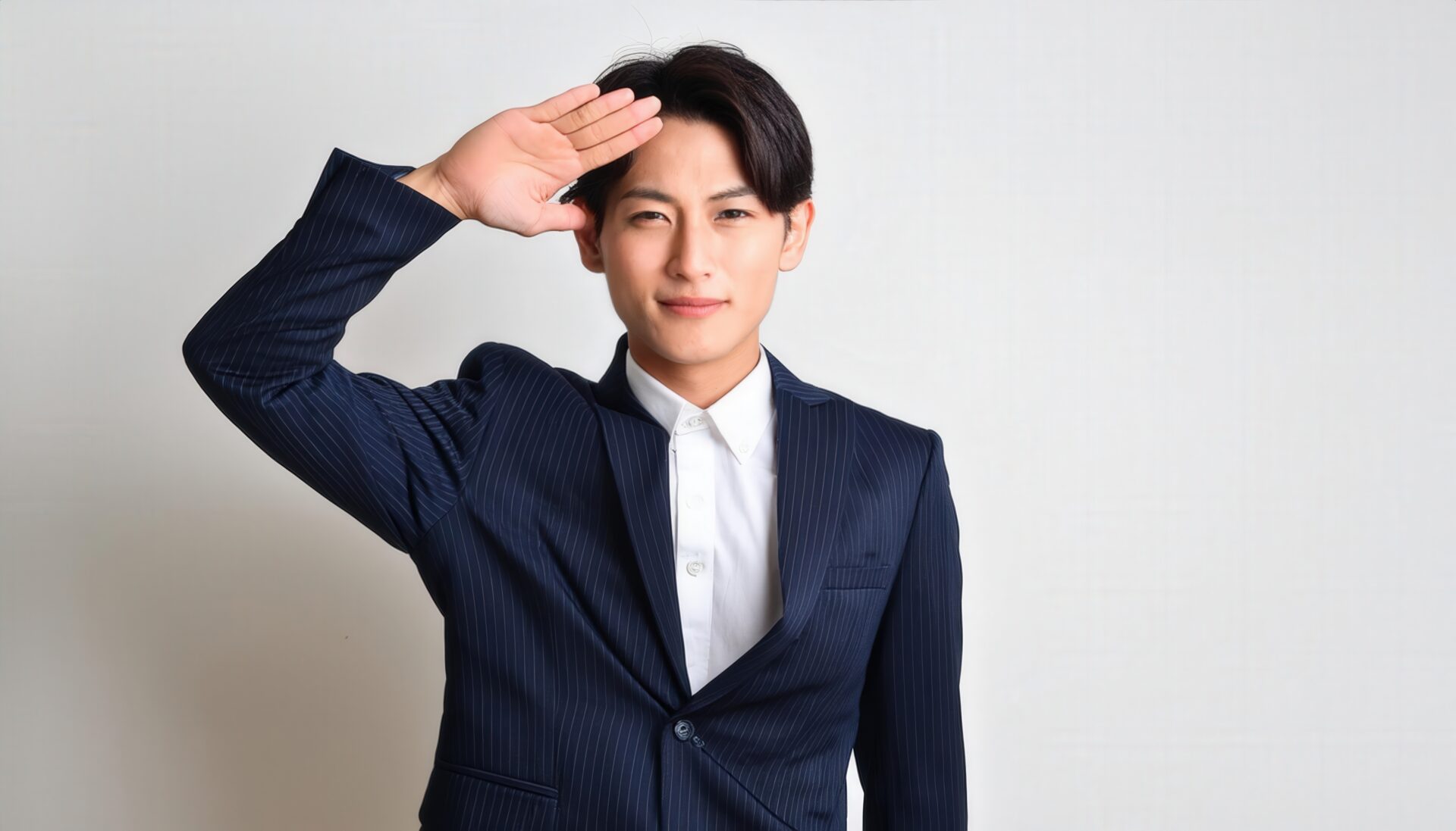 白背景でネイビースーツを着て敬礼する人物