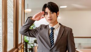 オフィスで敬礼するスーツ姿の人物