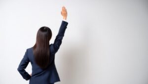 背面からスーツ姿で手を上げる人