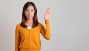 マスタード色のカーディガンで手を上げる人