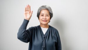 グレーのカーディガンで手を上げる高齢者