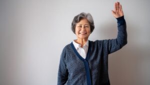 紺色のカーディガンで手を上げる高齢者