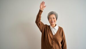 ブラウンのカーディガンで手を上げる高齢者