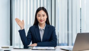 デスクに座り手を上げるスーツ姿の人