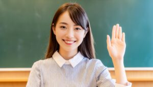 教室で挙手する笑顔の学生