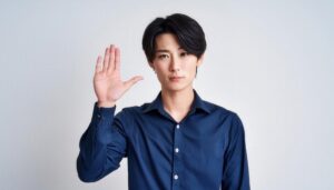 白背景で挙手する青いシャツの男性