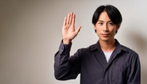 室内で挙手するダークシャツの男性