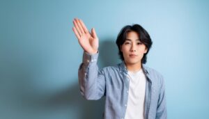 室内で挙手する青いシャツの人物