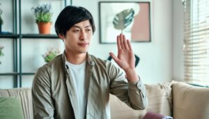 リビングで挙手するベージュシャツの人物