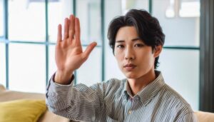 室内で挙手するストライプシャツの人物