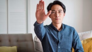 室内で挙手するメガネの人物
