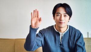 室内で挙手する青いトップスの人物