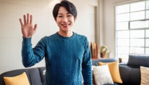 室内で挙手するブルーセーターの人物