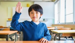 教室の机で片手を上げる子供