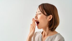 白背景であくびをする女性