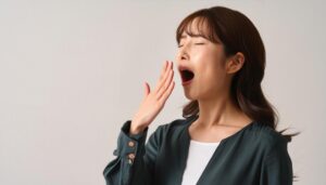 グレー背景であくびをする女性