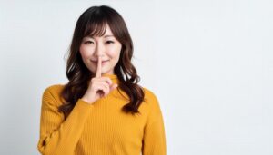 マスタード色のセーターで内緒ポーズをする人