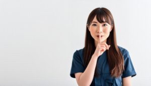 ネイビーのトップスで口元に指を当てる人