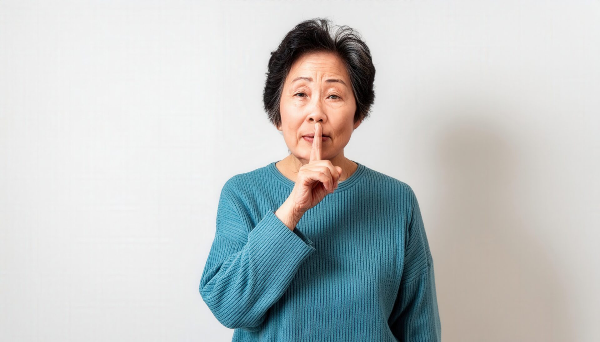 ショートヘアの人が口元に指を当てる