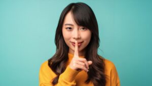 指で静かにと示す黄色い服を着た若者